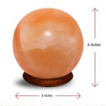 Ball shape Himalayan salt lamp with pink crystals and wooden base glowing warm amber light for home decor